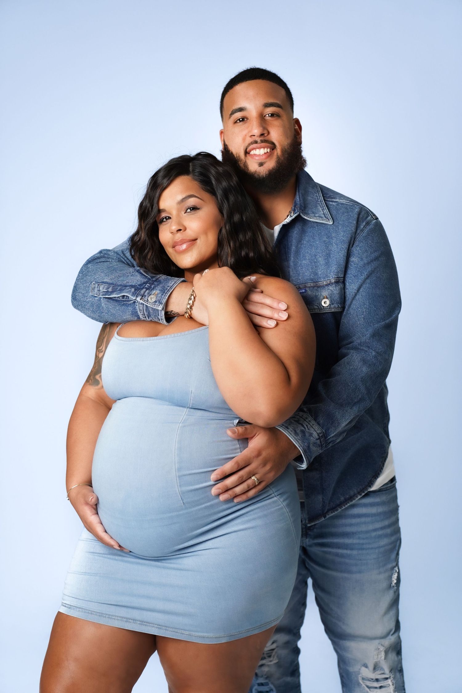 A couple wearing denim and light blue embraces while posing in four different romantic maternity photos.