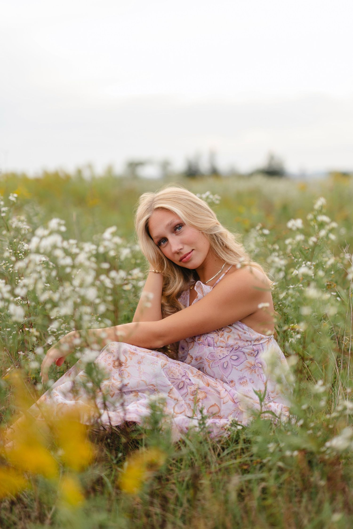 Light blue dress flows in a summer meadow at golden hour as tall grass and wildflowers sway in the breeze.