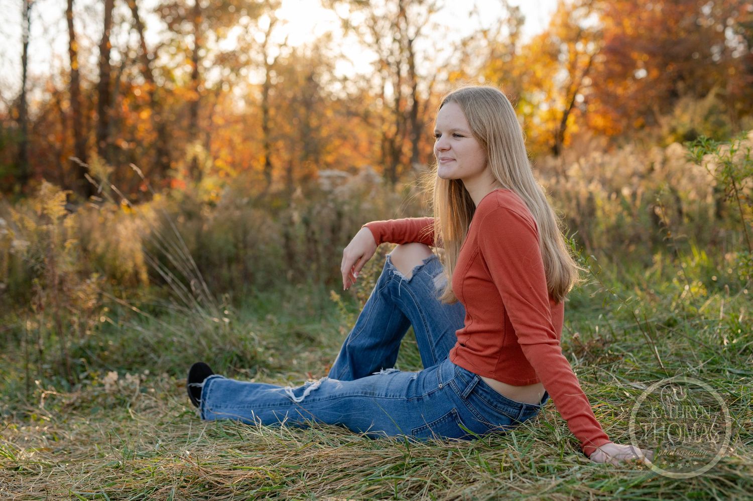 Relaxed outdoor portrait in autumn setting with casual attire and warm lighting.