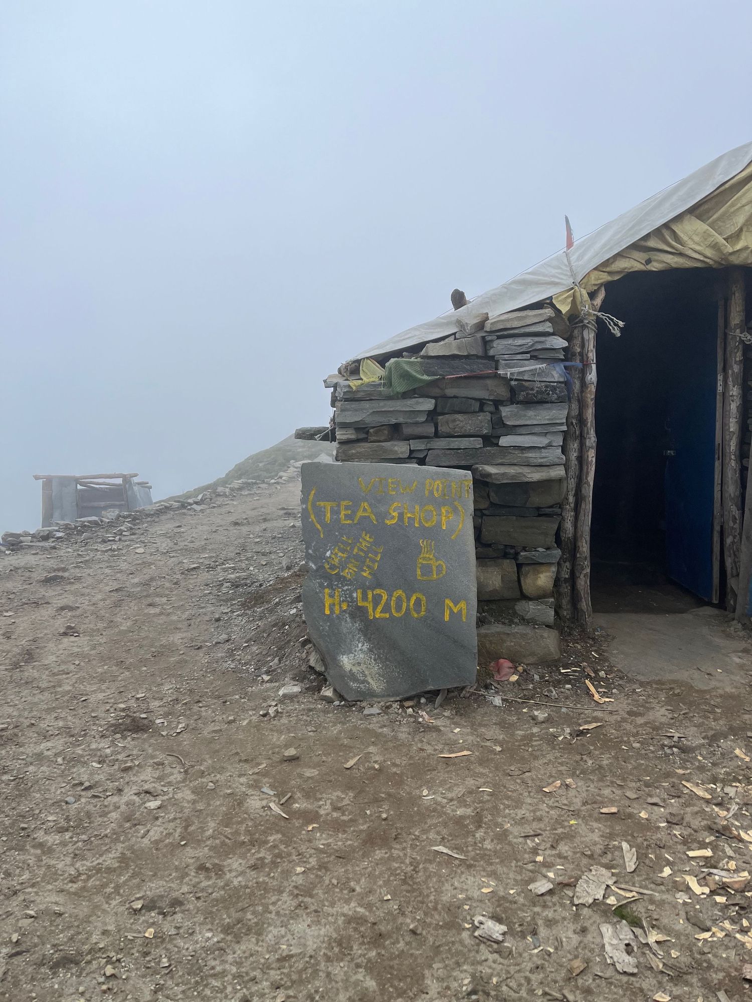 Stone shelter with elevation marker visible in foggy mountain conditions.