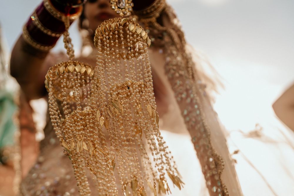 Ornate golden bridal jewelry and bangles adorned with intricate details glisten in soft lighting at an Indian wedding ceremony.