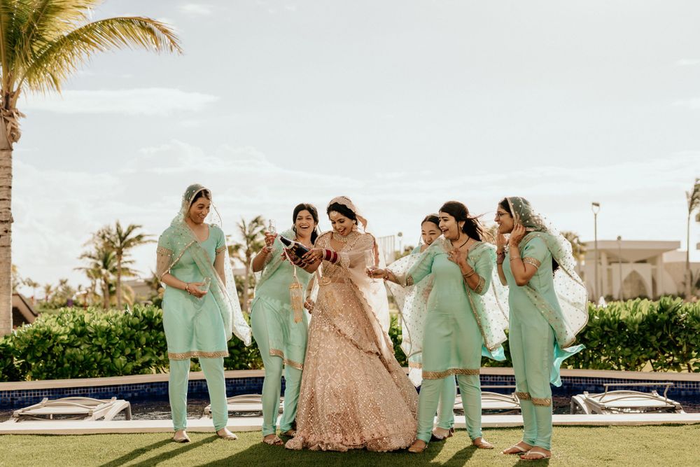 Wedding party in mint green outfits poses together on a sunny day with palm trees and tropical surroundings.