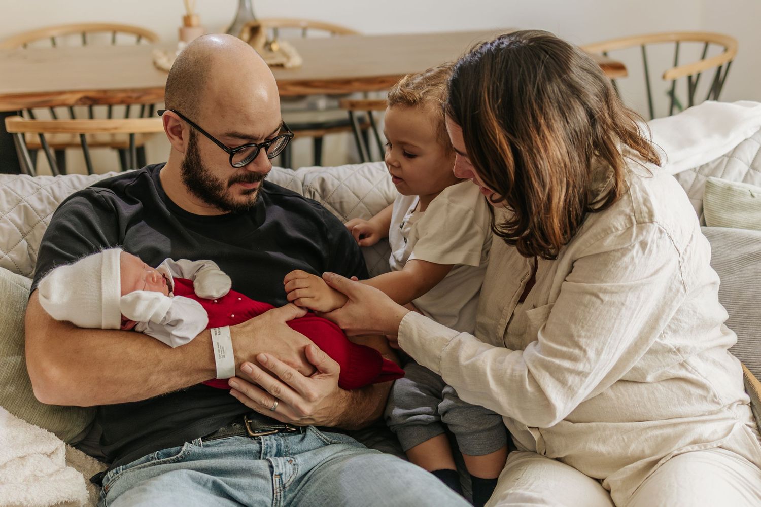 parents introducing their newborn baby to the oldest son, in their living room