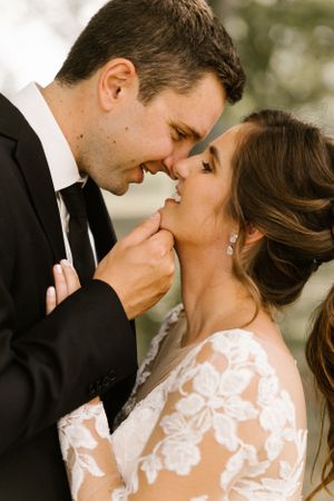 A romantic close-up of newlyweds sharing an intimate moment outdoors.