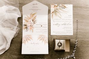 Wedding stationery suite with floral designs and a ring box in neutral tones.