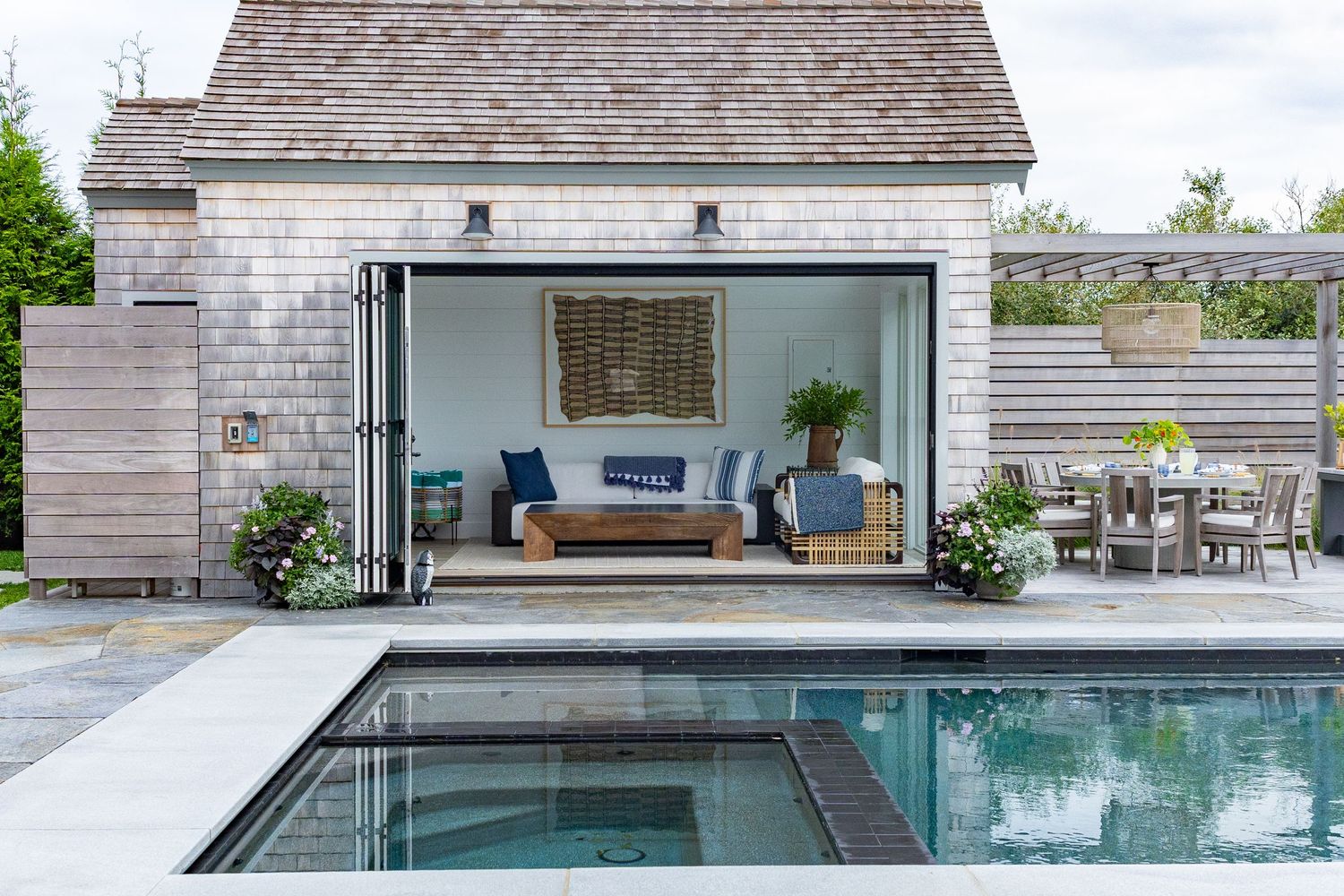 Modern pool house with sliding glass doors opens to a stylish lounge area beside a swimming pool on Nantucket, MA at a Interior Design shoot