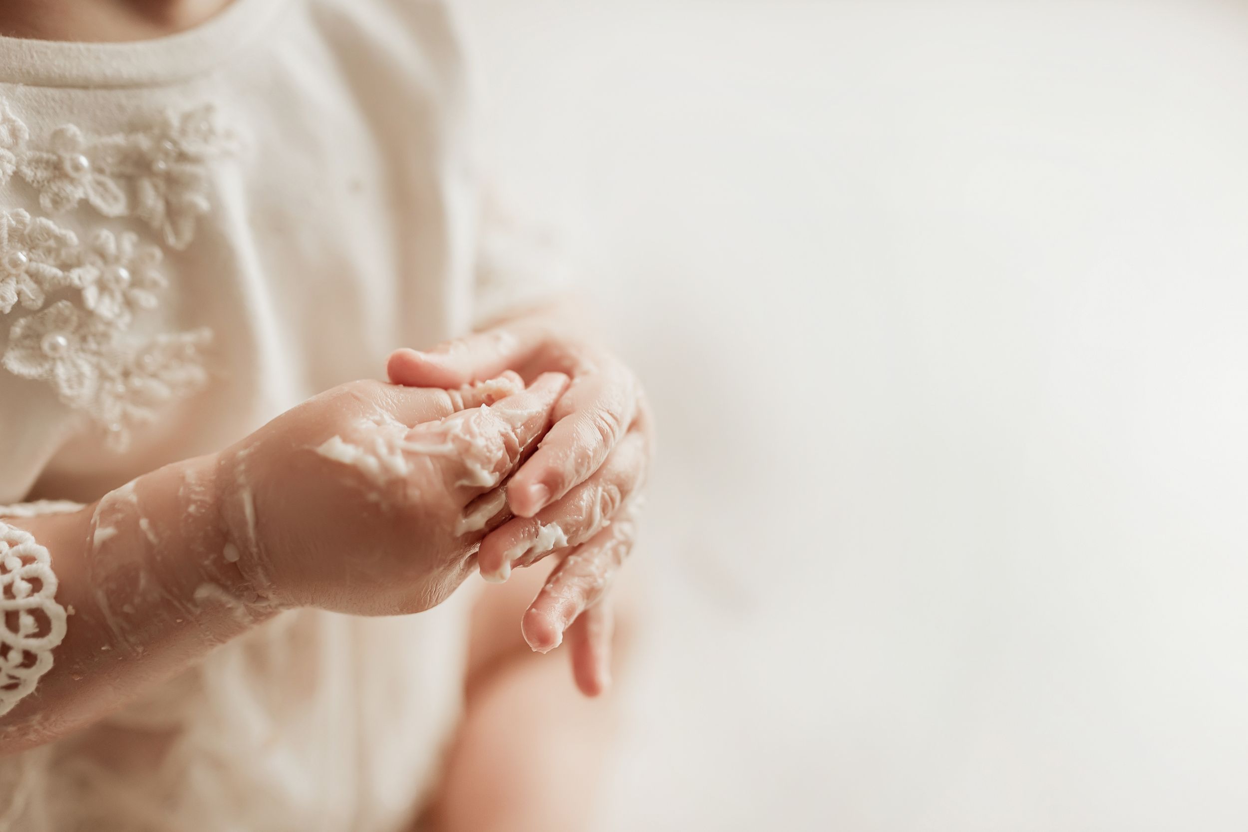 Delicate lace embellished sleeves with hands clasped together against a white background.