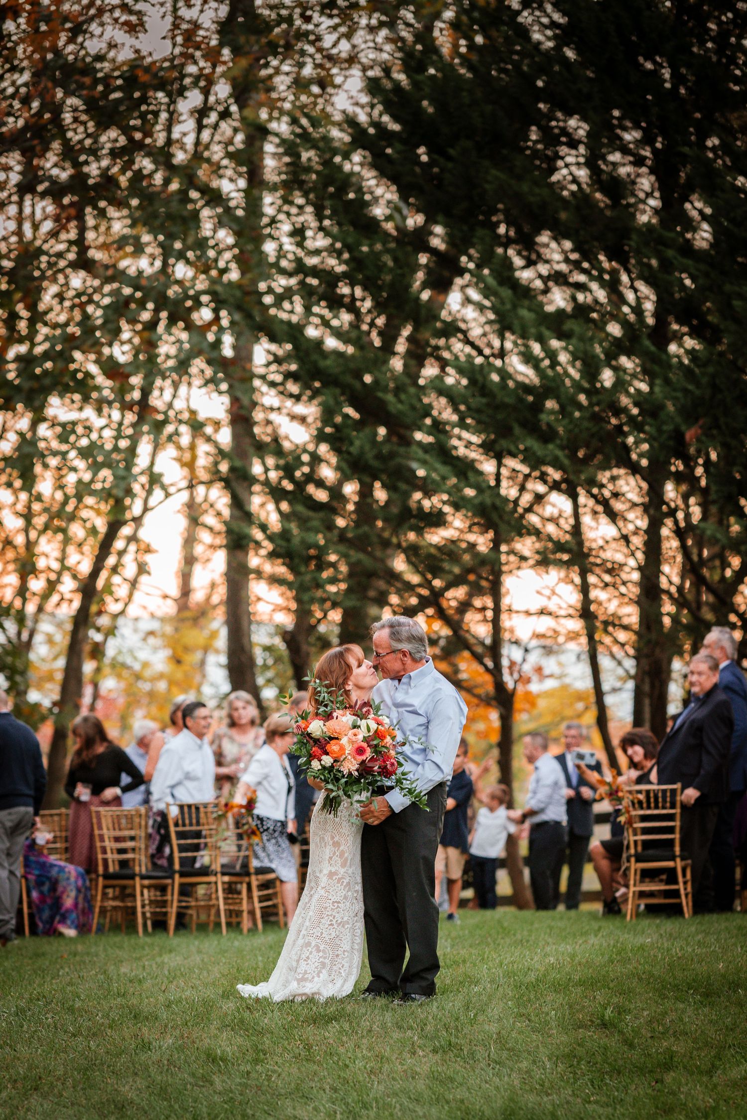 Outdoor wedding ceremony scene with trees and golden sunlight.