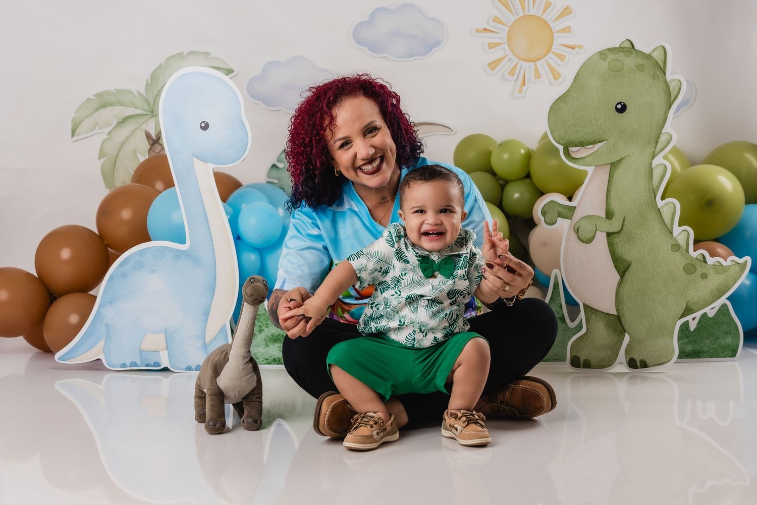 A joyful moment captured against a backdrop of cute dinosaur decorations and balloon arrangements.