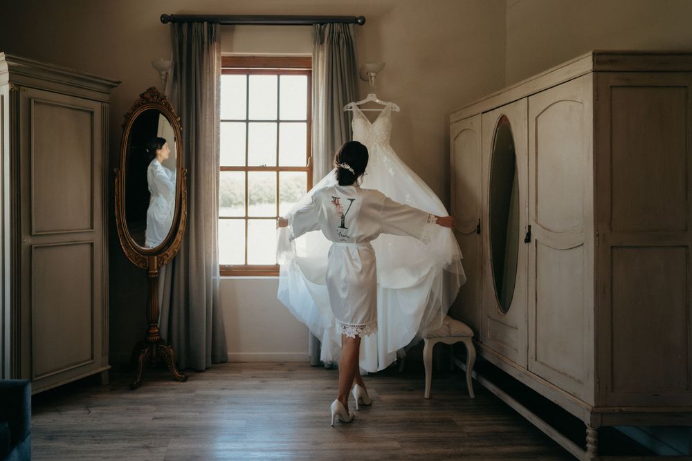 Wedding dress displayed gracefully in vintage-style dressing room with antique furniture and natural light.