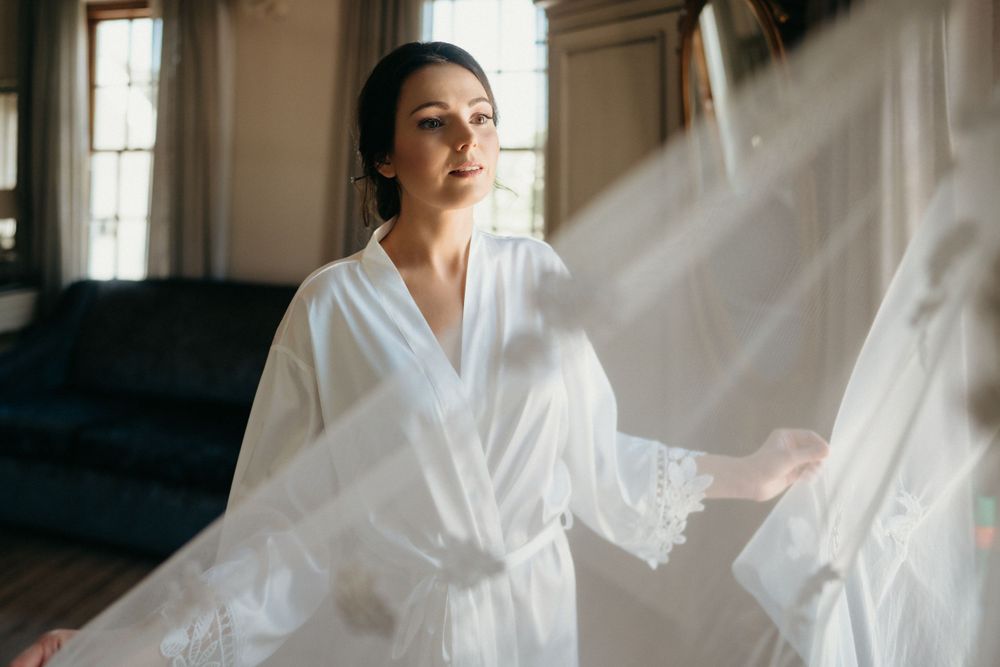 Morning light streams through a window into an elegant dressing room with flowing fabric.