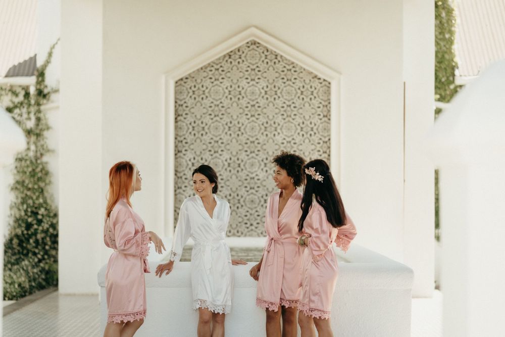 A group wearing matching pink robes poses near an ornate archway.