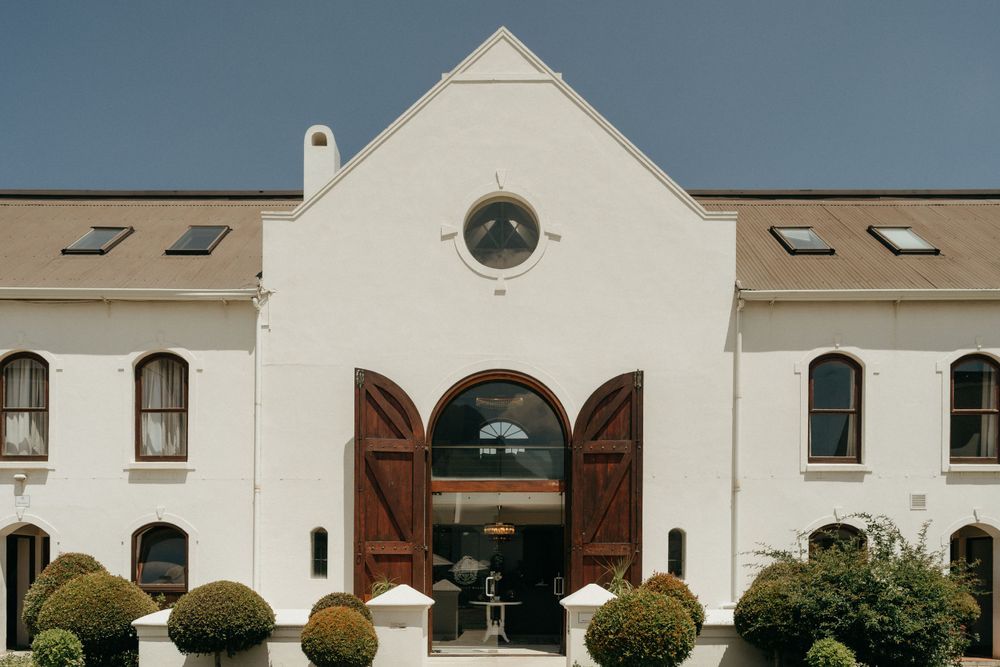 White Cape Dutch style building with wooden doors and circular window in classic architecture.