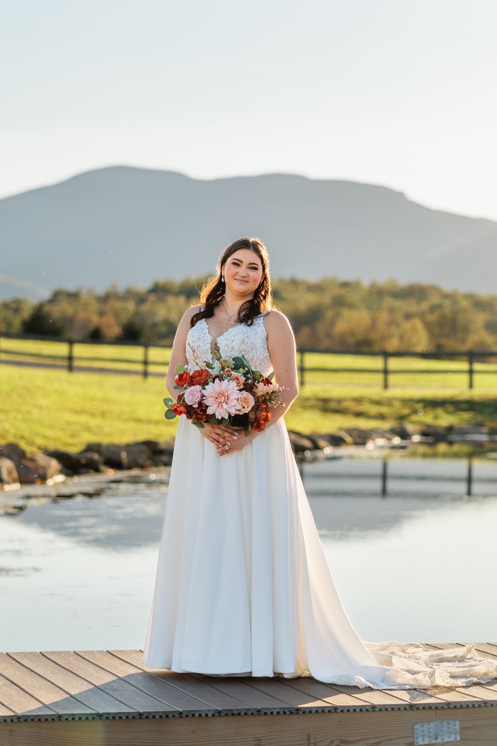 Beautiful bridal portrait with autumn mountains and pond reflection in background.
