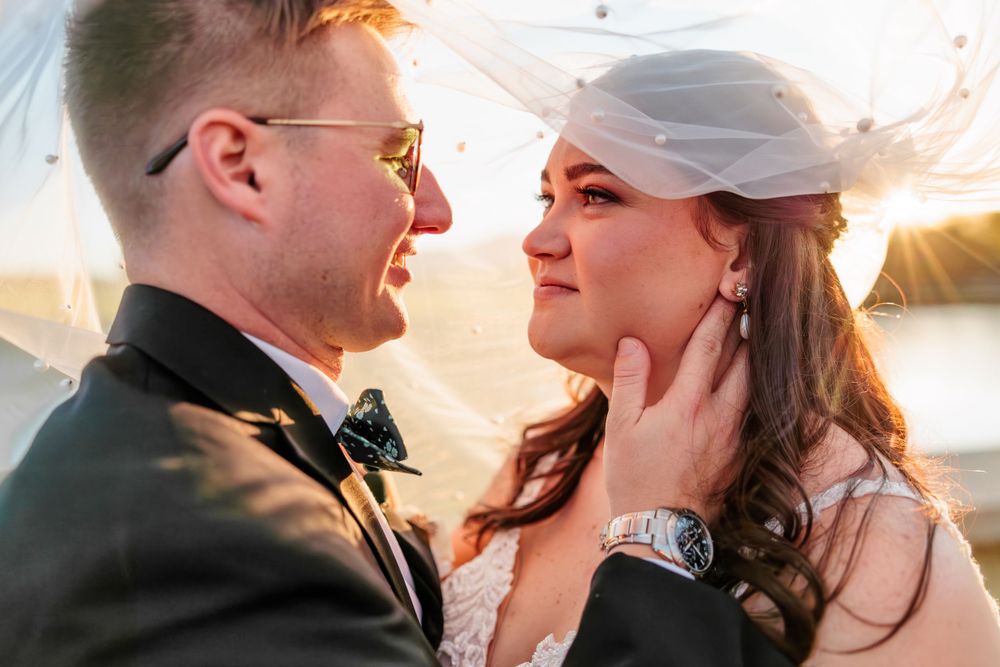 Intimate wedding portrait captured during sunset with bride's veil flowing in the breeze.