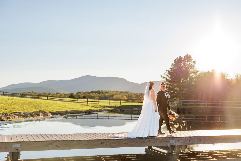 Scenic wedding photography on wooden deck with mountain landscape and golden sunlight.