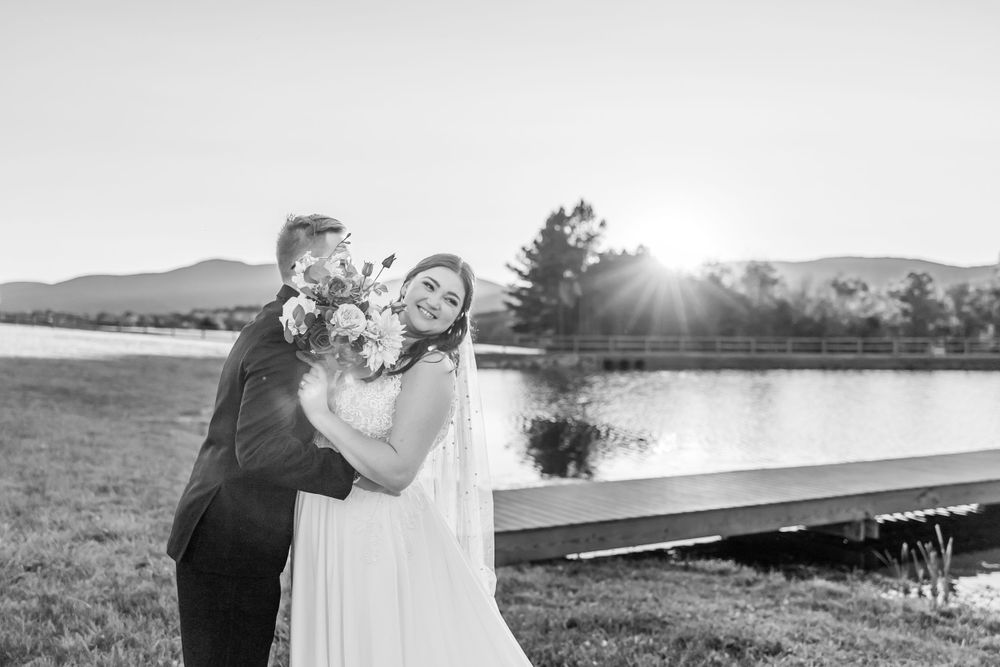 Black and white wedding portrait with sunburst and lake reflection.