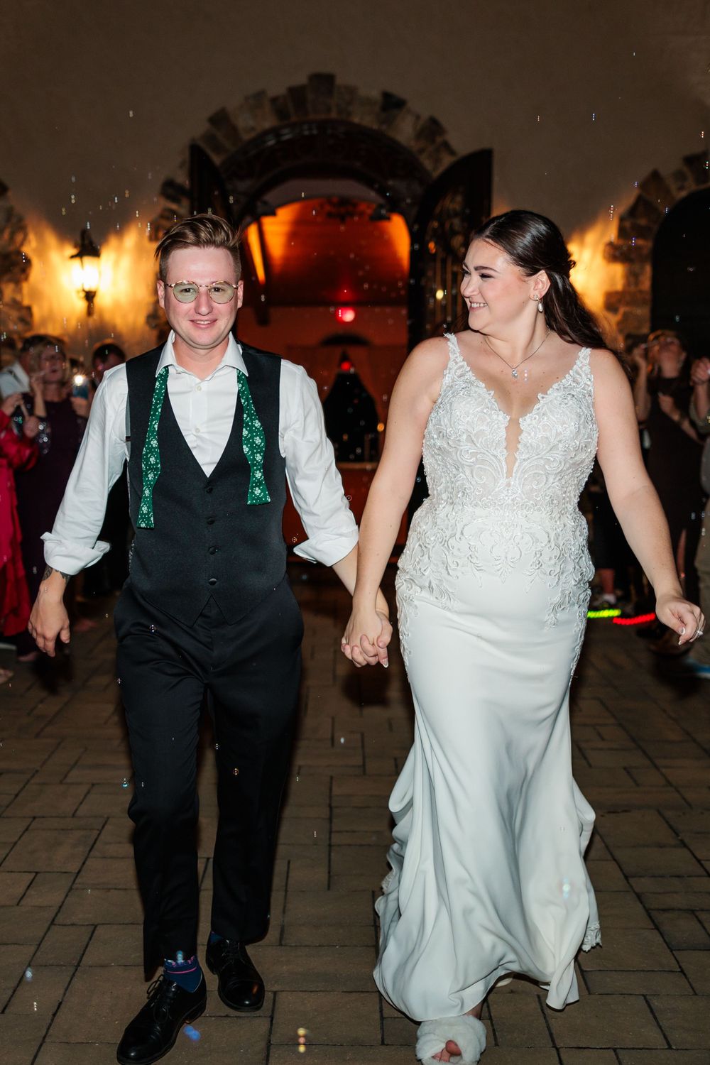 Wedding reception dance moment captured under warm lighting and stone archway.