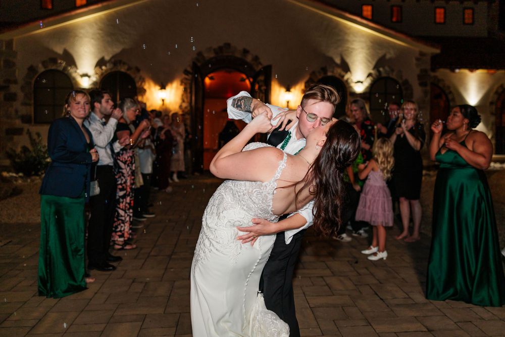 Couple shares a romantic dip during their wedding dance as guests watch from the sidelines.