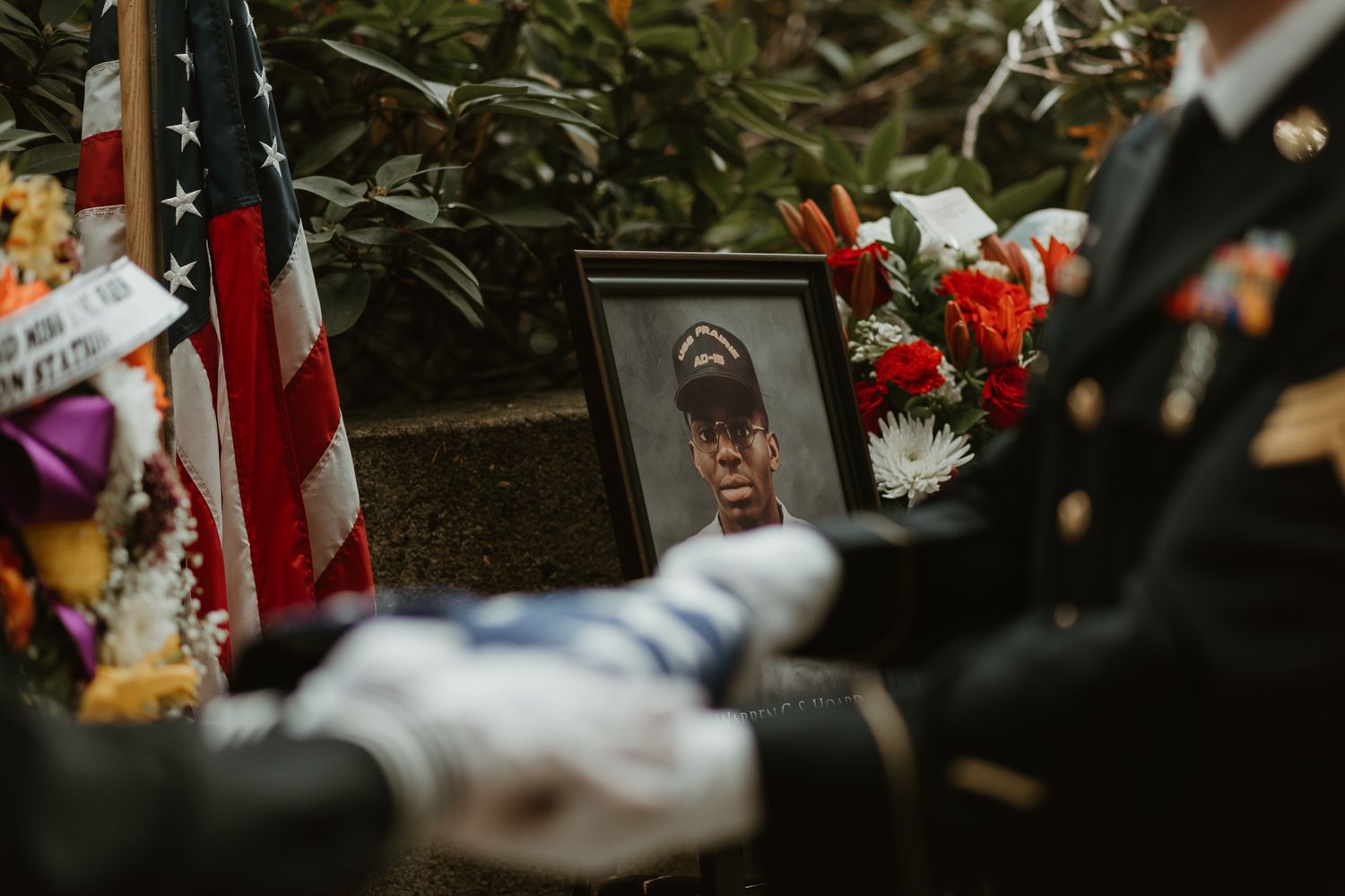 A memorial display with an American flag and flowers at a gravesite.