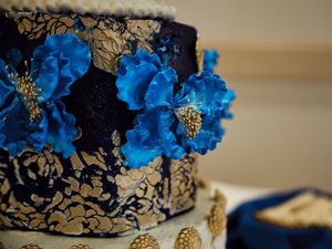 Vibrant blue floral arrangements with gold accents create an elegant wedding reception table centerpiece.