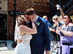 Wedding guests shower the happy couple with confetti during an outdoor celebration.