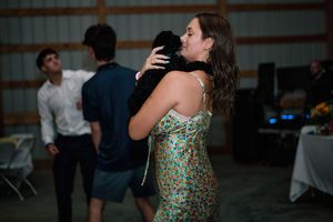 A couple dances together at an indoor event while other guests mingle in the background.