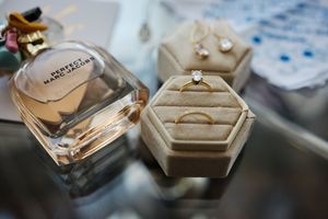 Close-up view of luxury perfume bottles and jewelry arranged on a reflective surface with soft lighting.