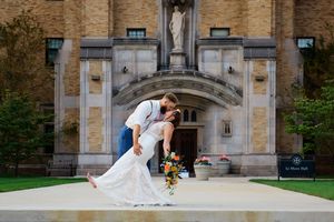 A romantic dip pose in front of an ornate stone church entrance with a statue and sunflowers.