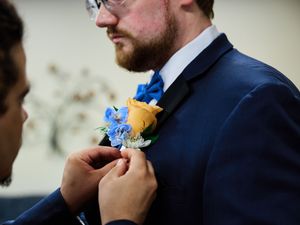 Adjusts a bright blue boutonniere on a groom's suit.

Indiana Weddings
Illinois Weddings
Michigan Weddings
Weddings