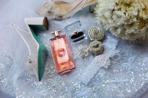 Wedding accessories including perfume bottles, jewelry, and white hydrangea flowers arranged on a light surface.