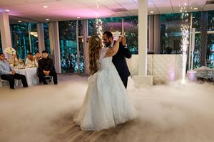 Dancers move gracefully across a misty dance floor with dramatic lighting effects at an elegant wedding reception.