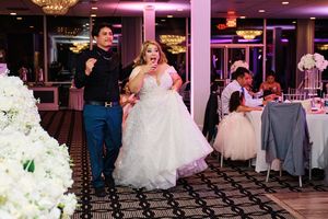 A couple makes their grand entrance at an elegant wedding reception with crystal chandeliers and floral decor.