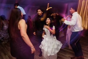 People dancing together on a dance floor illuminated by purple lighting at a wedding reception.