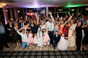 Wedding reception dance floor filled with guests celebrating under colorful lighting.