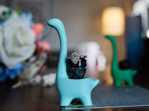A small teal dinosaur figurine holds wedding rings.

Indiana Weddings
Illinois Weddings
Michigan Weddings
Weddings
