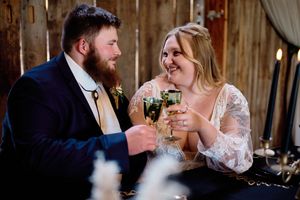 A couple shares a romantic moment during a toast at their rustic barn wedding reception.