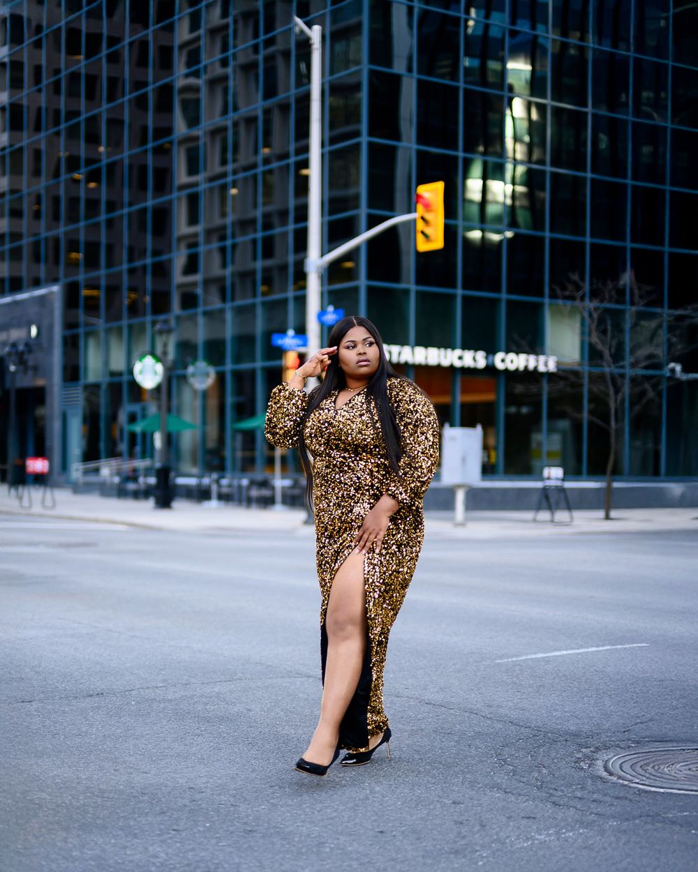 A woman in a leopard print dress walks along an urban street with Starbucks and office buildings visible in the background.