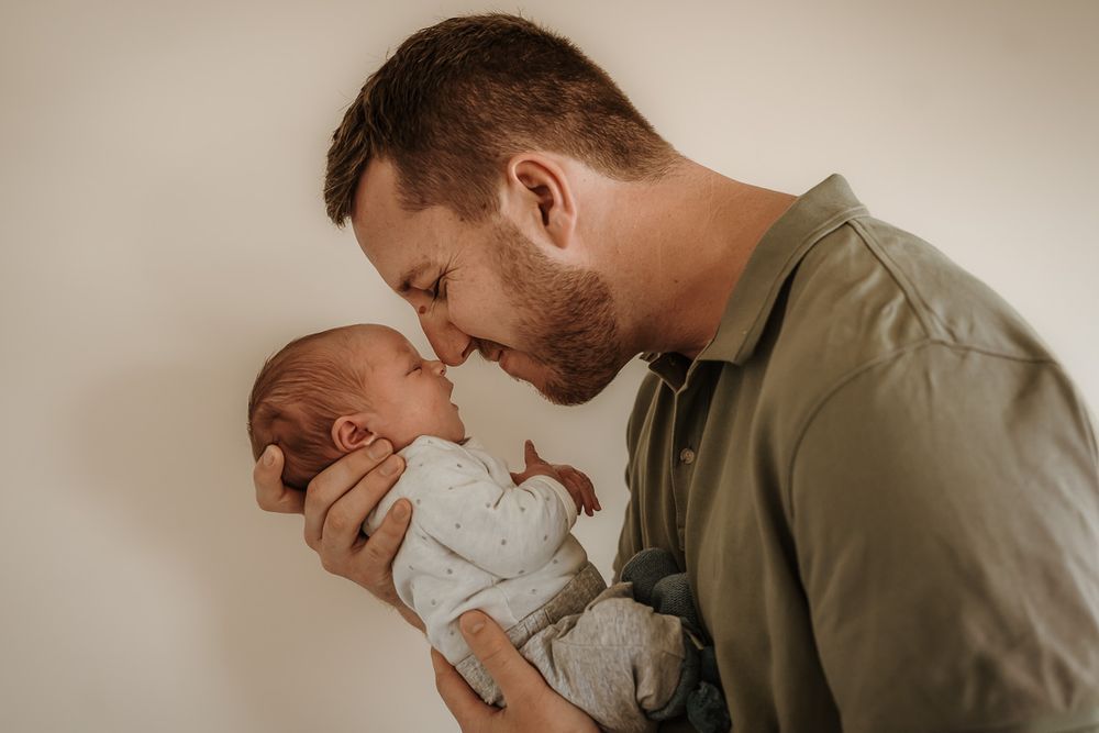 Tender moment between parent and newborn baby in soft natural light.