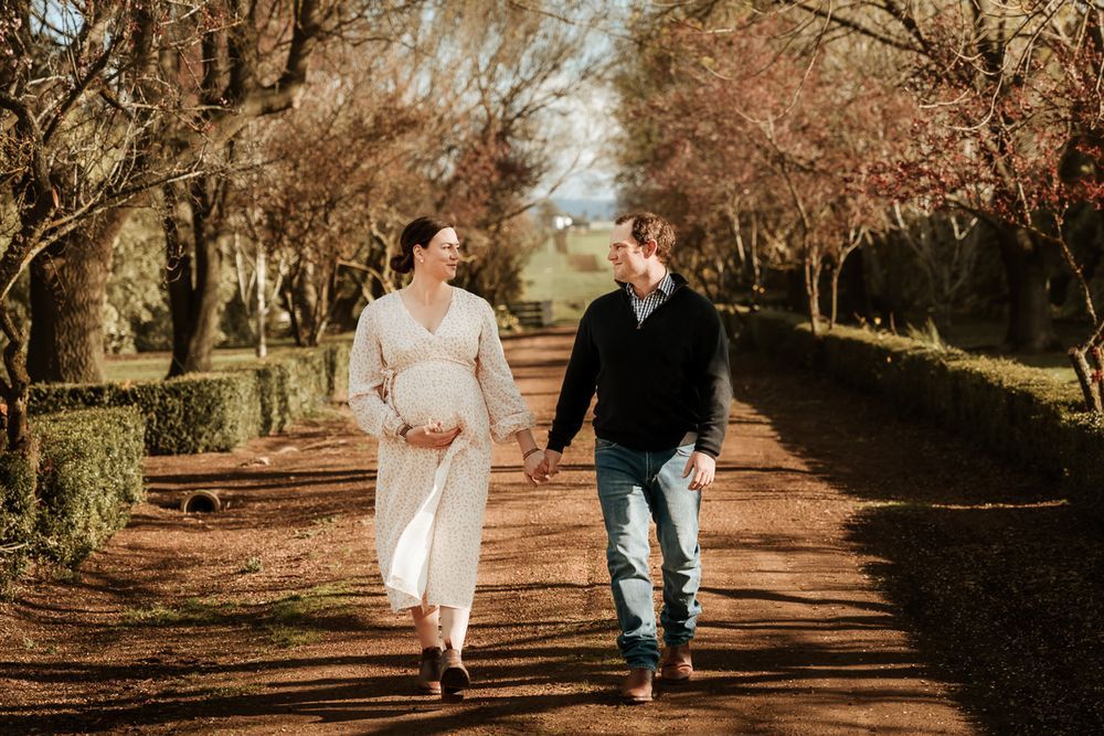 Couple walking together on tree-lined path during autumn.