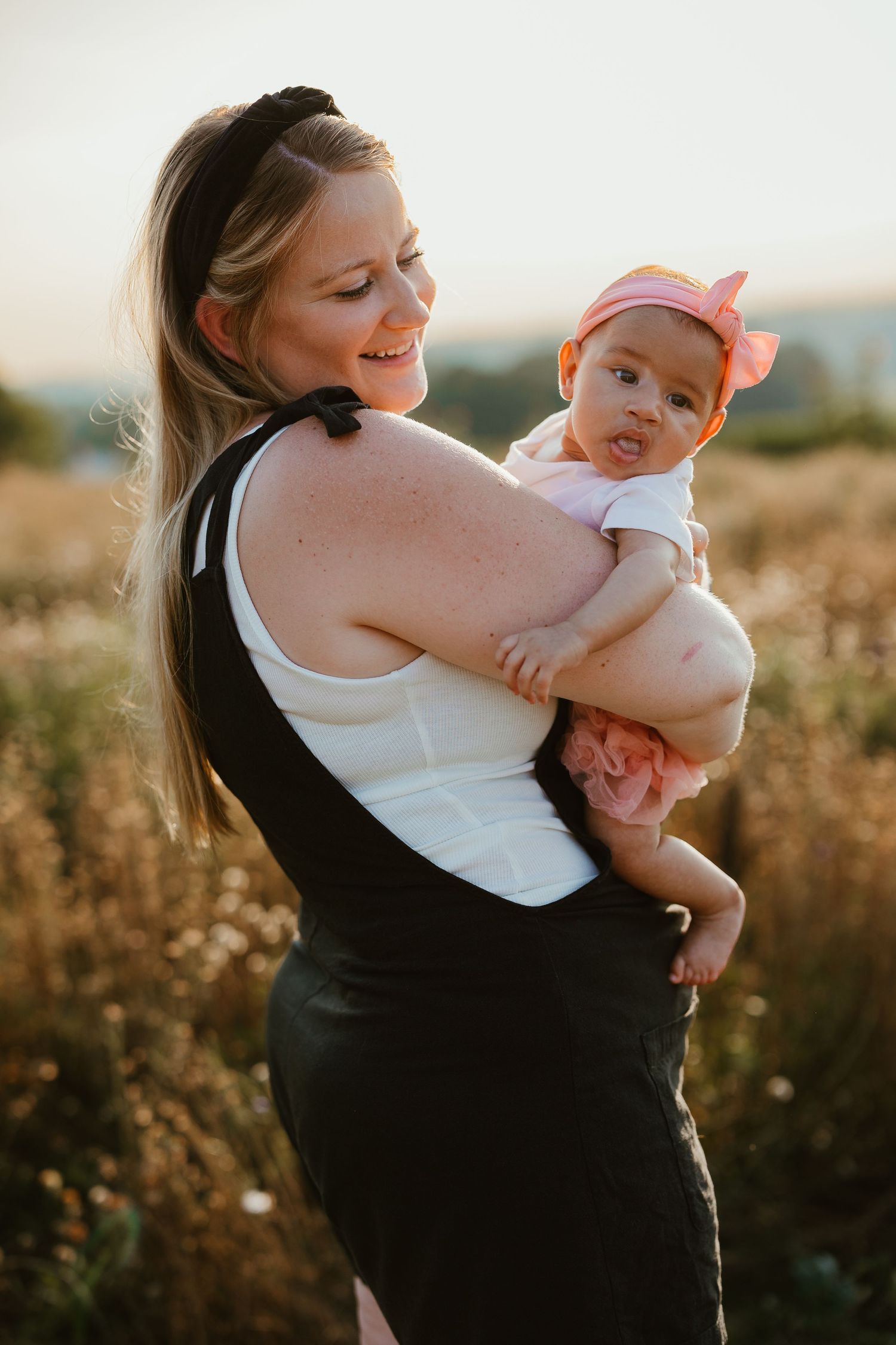 Sweet moment between parent and infant in sunset lighting against a natural outdoor backdrop.