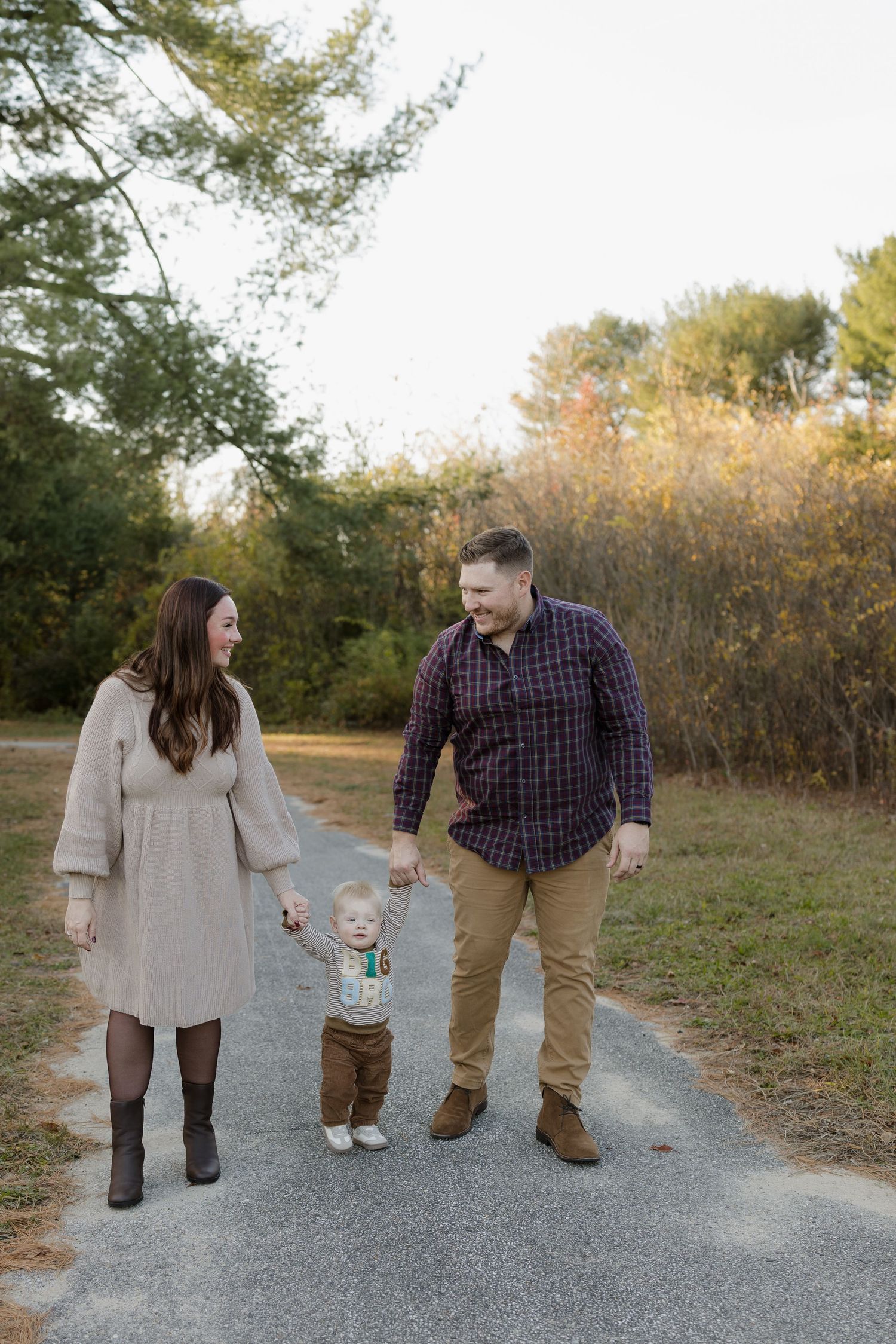 Family walking and playing together on a gravel path during autumn with trees in the background.