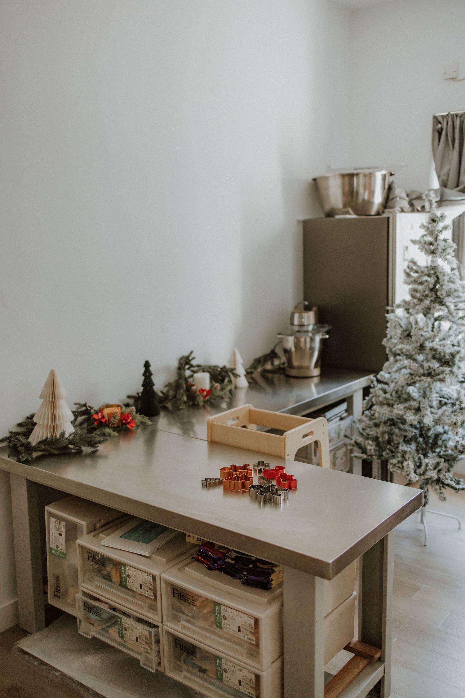 A festive kitchen island decorated with Christmas garland, cookie cutters, and a flocked Christmas tree in the background.