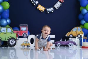 Transportation themed birthday setup with toy cars, trains, and blue balloon decorations.