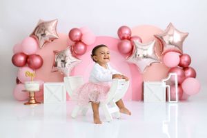 Pink and white first birthday setup with star balloons and decorative blocks.