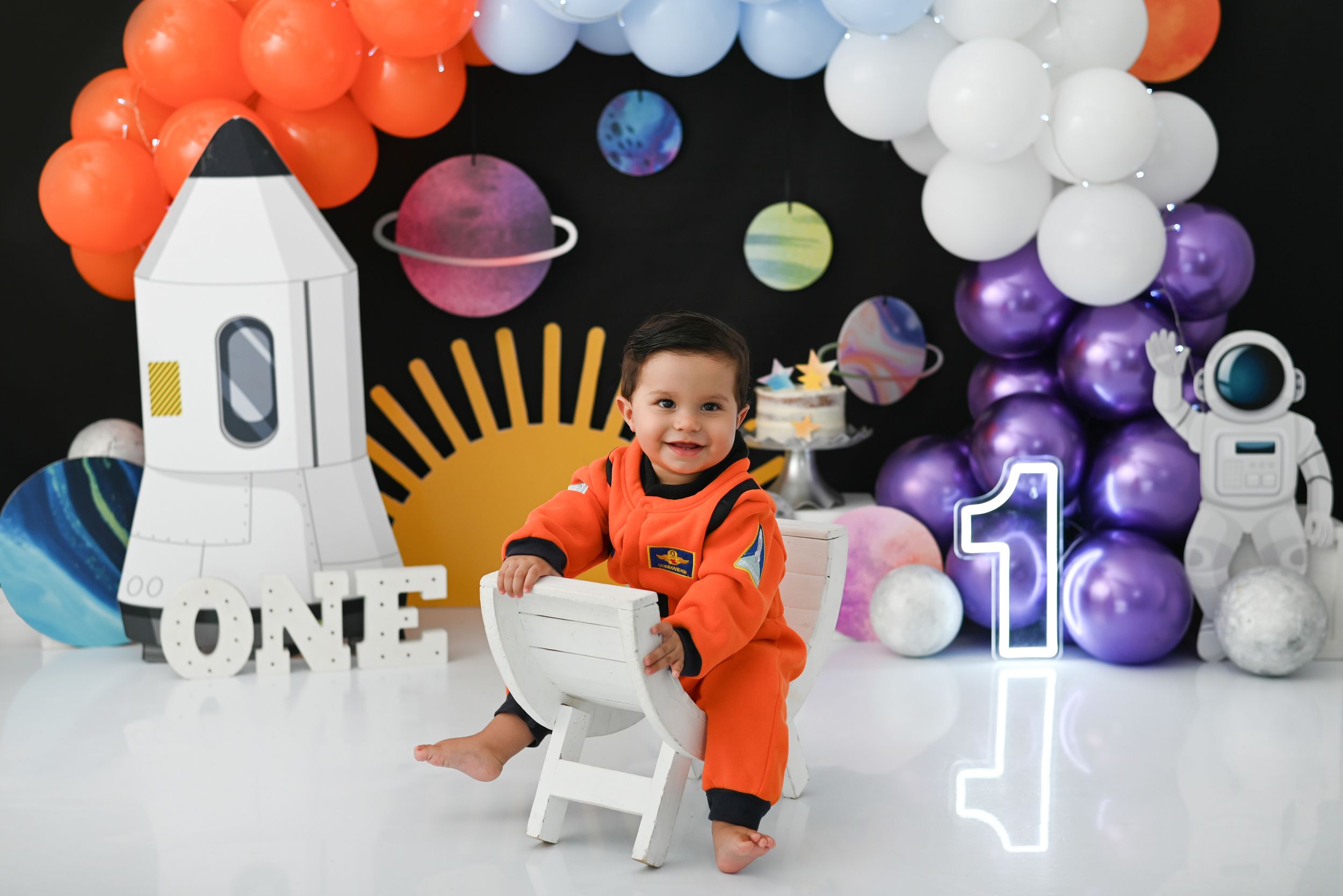 Outer space themed photo setup with orange and purple balloons, rockets and planets.