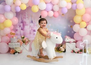 Magical unicorn themed first birthday setup with pastel balloons and rocking horse.