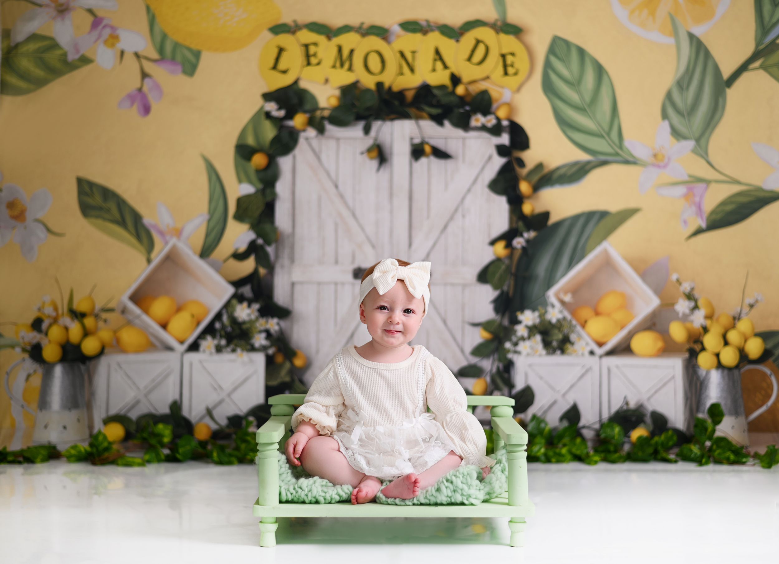 A decorated scene with white wooden doors, floral garlands, yellow flowers and green foliage backdrop for a photo setting.