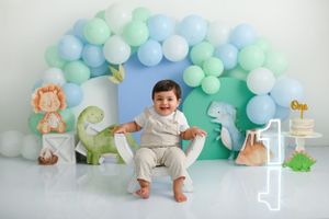 Dinosaur themed first birthday setup with blue and mint balloon arch.