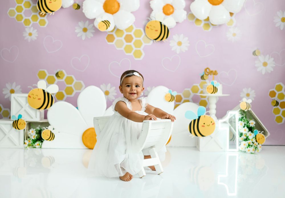 Bee and daisy themed photo setup with honeycomb pattern and balloon decorations.
